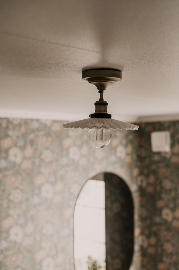 Stropná lampa Cobbler s tienidlom z plisovaného skla bielej farby visiaca zo stropu.