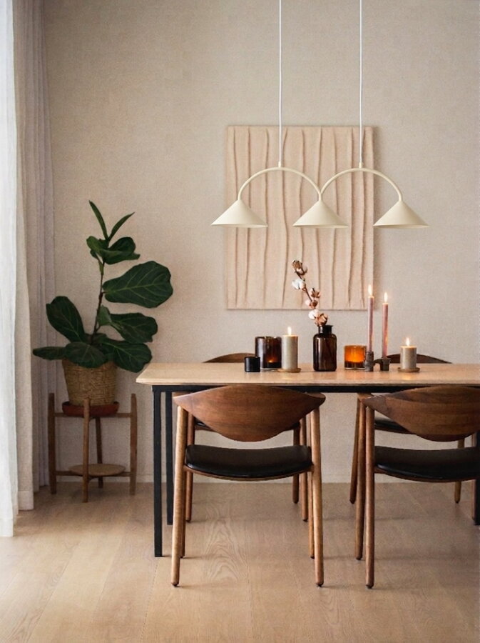 Béžová závesná lampa s troma trojuholníkovými tienidlami nad prestretým jedálenským stolom.