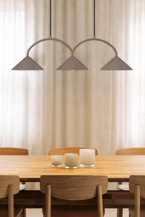 Hnedá závesná lampa s troma trojuholníkovými tienidlami nad jedálenským stolom s troma béžovými svietnikmi na čajovú sviečku.
