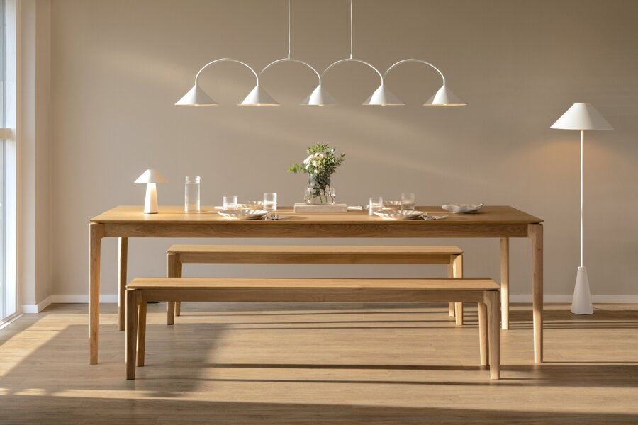 Biela závesná lampa s piatimi trojuholníkovými tienidlami nad prestretým jedálenským stolom.