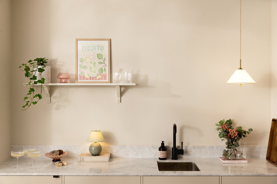 Závesná lampa Iris krémovej farby nad kuchynskou linkou.