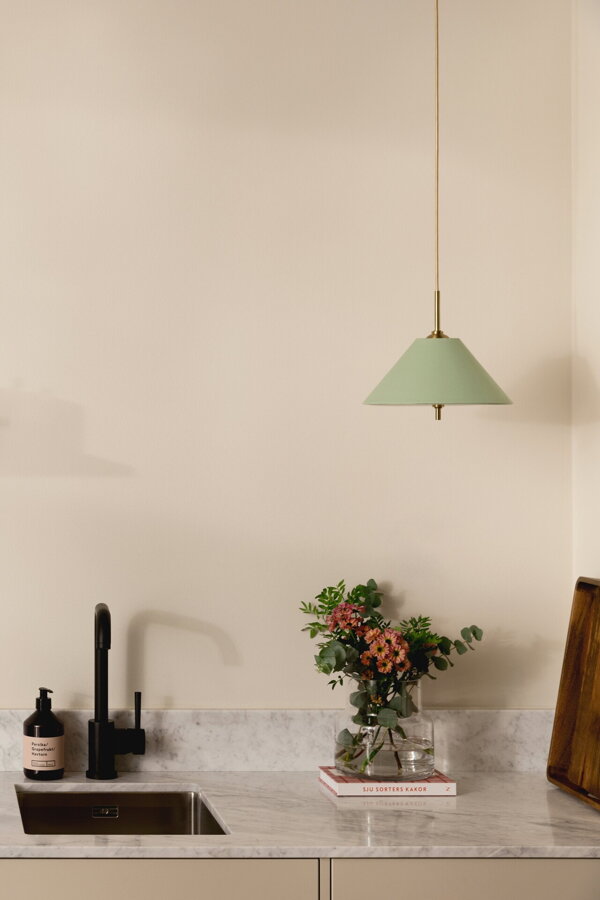 Závesná lampa Iris s bavlneným tienidlom jemnej zelenej farby nad kuchynskou linkou.