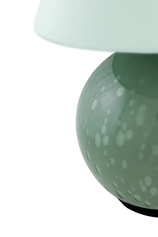 Detail na okrúhlu základňu lampy z ručne fúkaného skla zelenej farby.