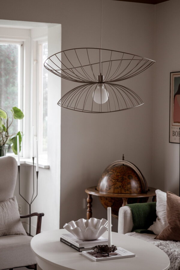 Dizajnová závesná lampa Ray s kovovým tienidlom v hnedosivej farbe v obývačke nad stolom.