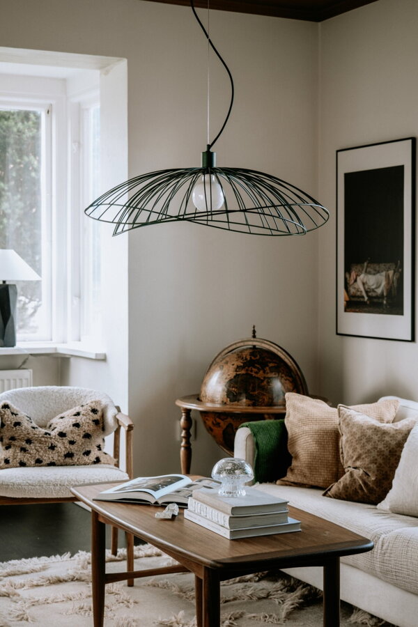 Zelená závesná kovová lampa nad konferenčným stolíkom v obývačke.