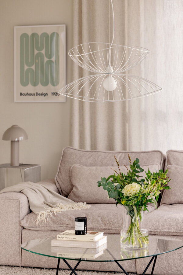 Biela kovová závesná lampa Ray v obývačke nad konferenčným stolíkom.