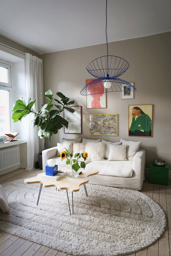 Modrá závesná kovová lampa nad konferenčným stolíkom v obývačke.