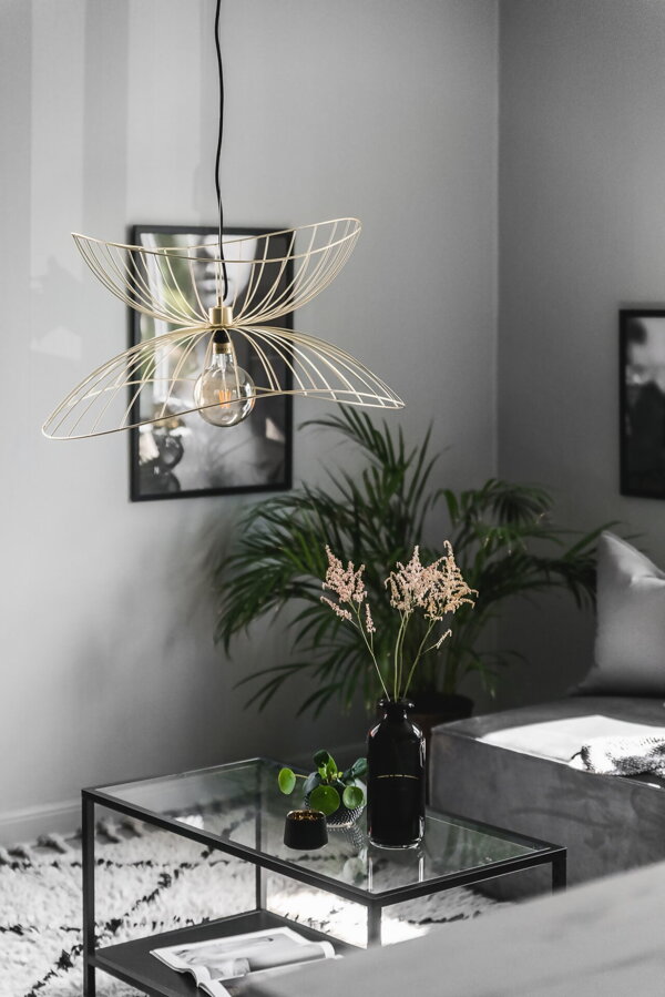 Kovová závesná lampa vo farbe brúsenej mosadze nad konferenčným stolíkom v obývačke.