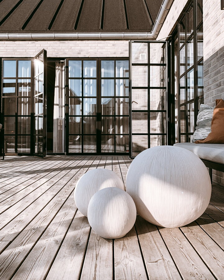 Tri biele guľaté vonkajšie lampy na terase pred domom.