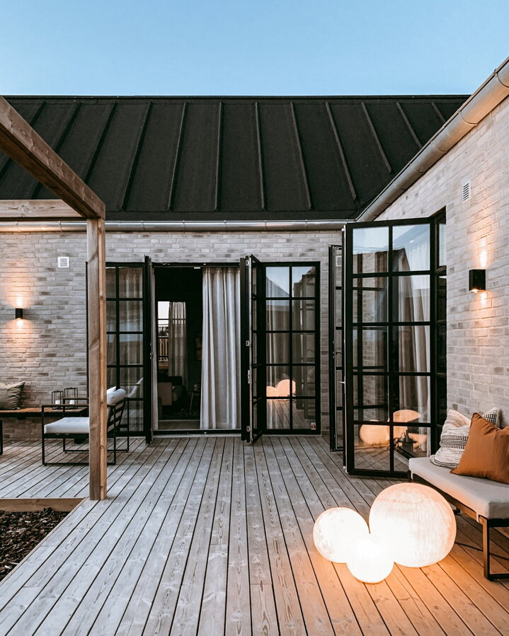 Tri svietiace biele guľaté vonkajšie lampy na terase pred domom.