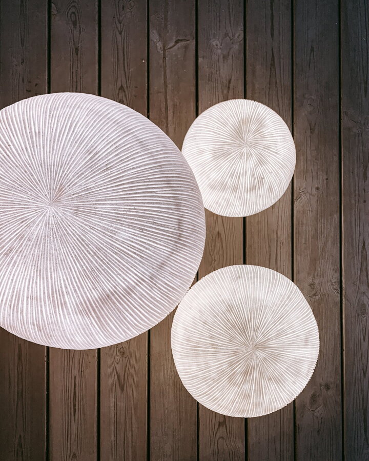 Tri biele svietiace guľaté vonkajšie lampy vo večernej atmosfére.