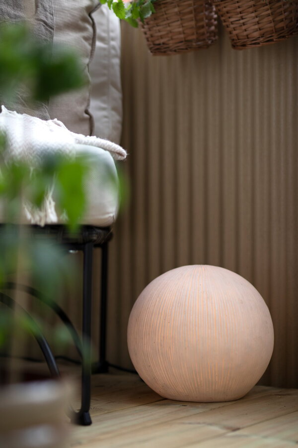 Svietiaca lampa v tvare gule na terase pri záhradnej pohovke.