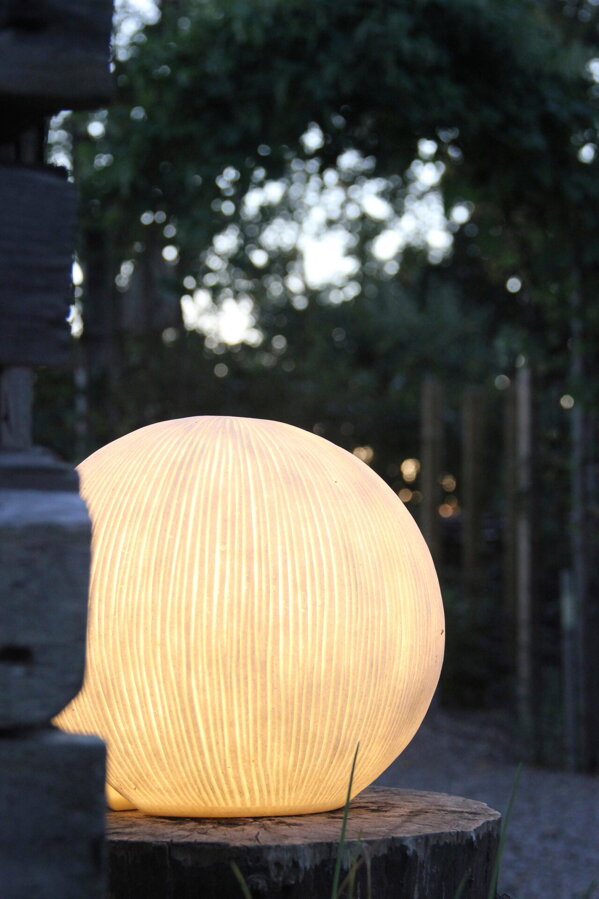 Svietiaca lampa v tvare gule v záhrade v podvečernej atmosfére.