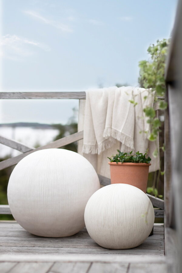 Dve biele guľaté vonkajšie lampy na terase.