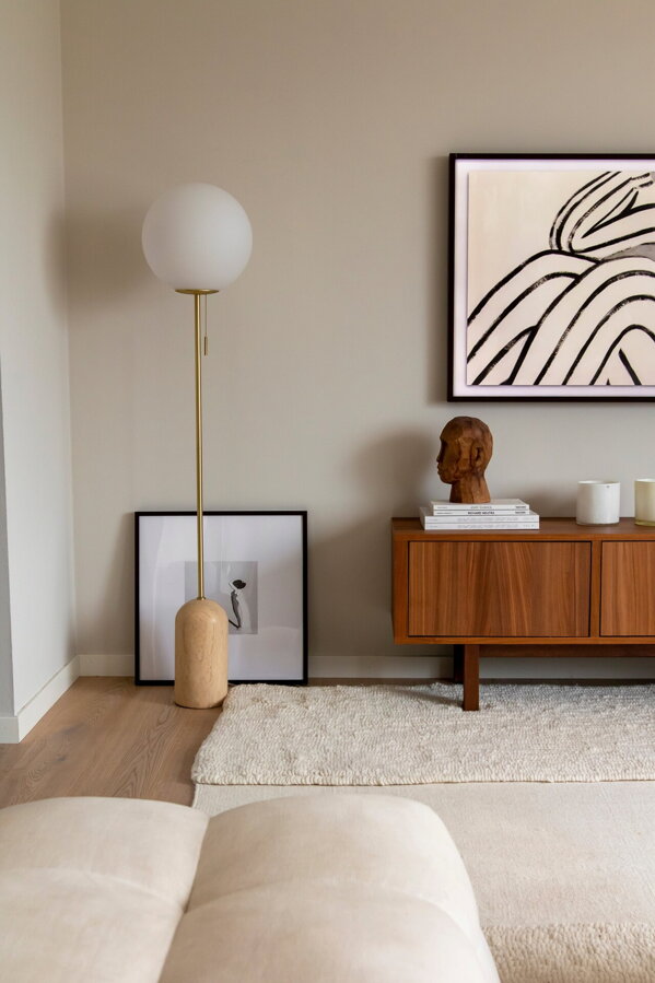 Stojanová lampa s travertínovo mramorovou základňou a bielym tienidlom z opálového skla v rohu obývačky.