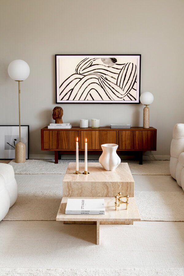 Stojanová lampa s travertínovo mramorovou základňou a bielym tienidlom z opálového skla v rohu obývačky.