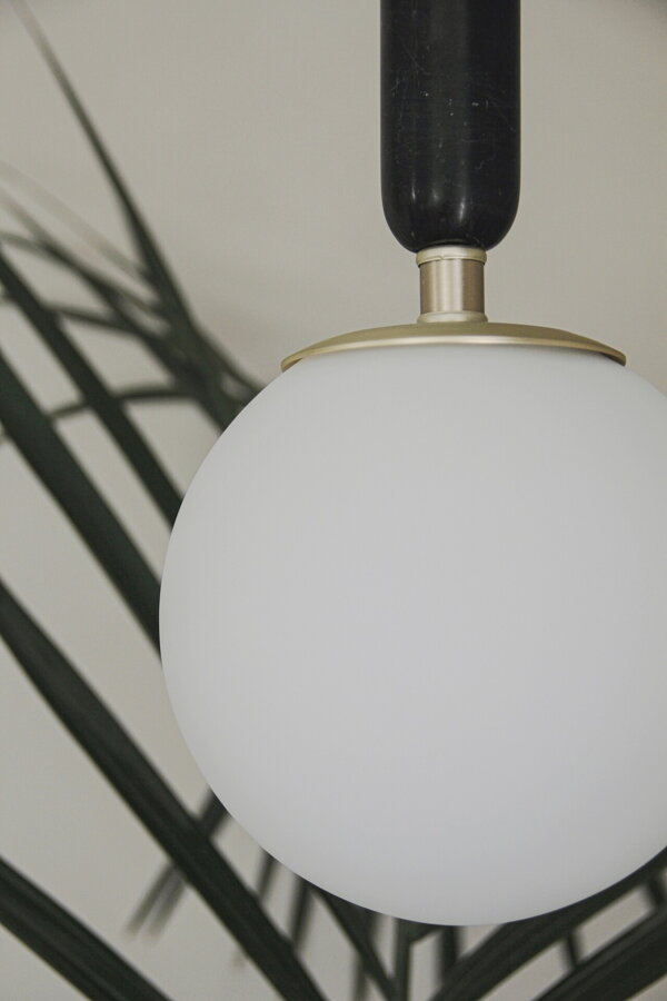 Závesná lampa Torrano s masívnou čiernou mramorovou základňou a s jemným tienidlom z bieleho opálového skla.