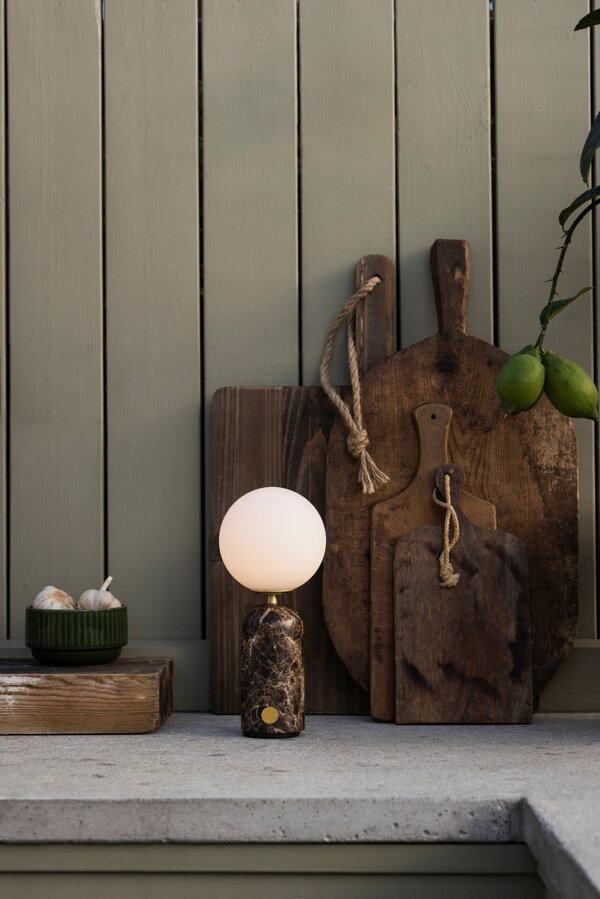 Stolová lampa Torrano s masívnou hnedou mramorovou základňou a s jemným tienidlom z bieleho opálového skla na kuchynskej linke.