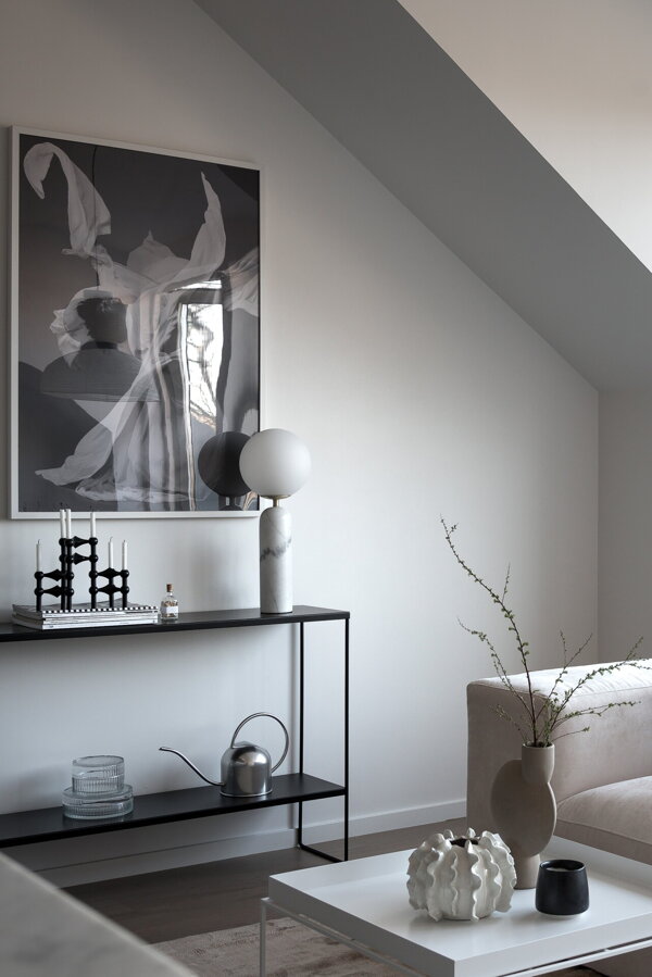 Biela mramorová stolová lampa na konzolovom stolíku pri stene v obývačke.