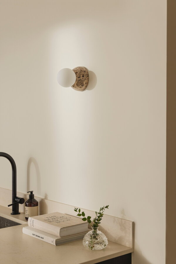 Nástenná lampa Torrano s masívnou hnedou mramorovou základňou a s jemným tienidlom z bieleho opálového skla v kuchyni nad umývadlom..