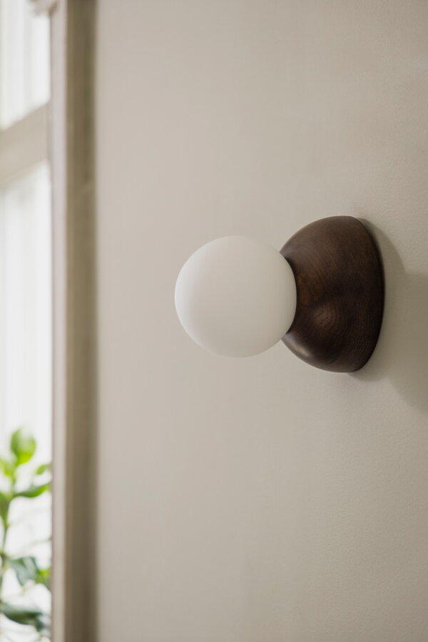 Dizajnová nástenná lampa Torrano s masívnou hnedou dubovou základňou a s jemným tienidlom z bieleho opálového skla.