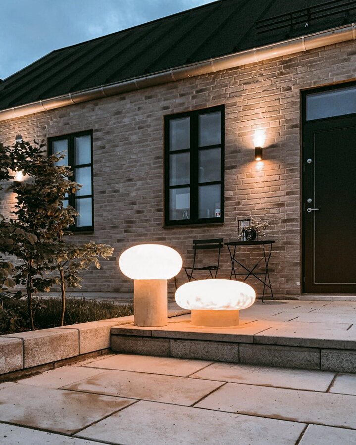 Rozsvietené sivé exteriérové stojanové lampy Umfors pred domom vo večernej atmosfére.