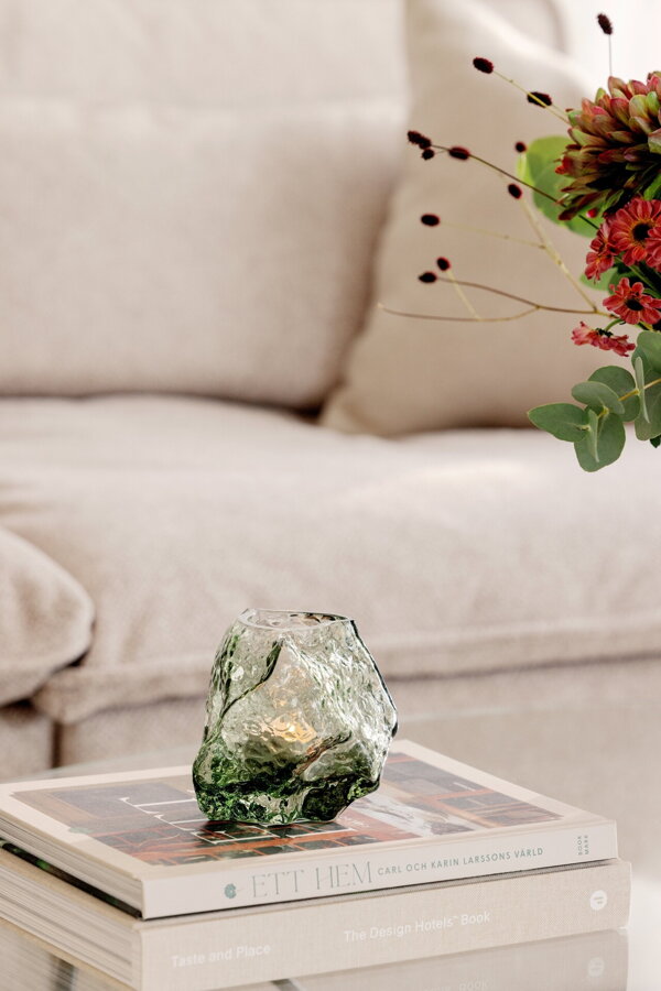 Zelený svietnik Valerie z ručne fúkaného skla položený na kôpke kníh.