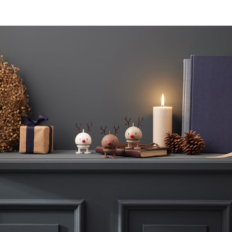 Figúrky Hoptimist položené na komode pri zapálenej sviečke.