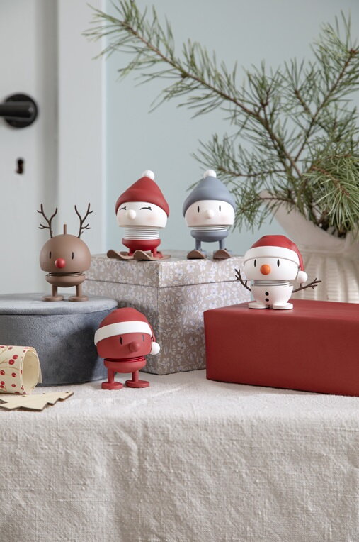 Figúrky Hoptimistov z kolekcie Christmas rozostavaných na vianočných balíčkoch pod ihličnatými vetvičkami