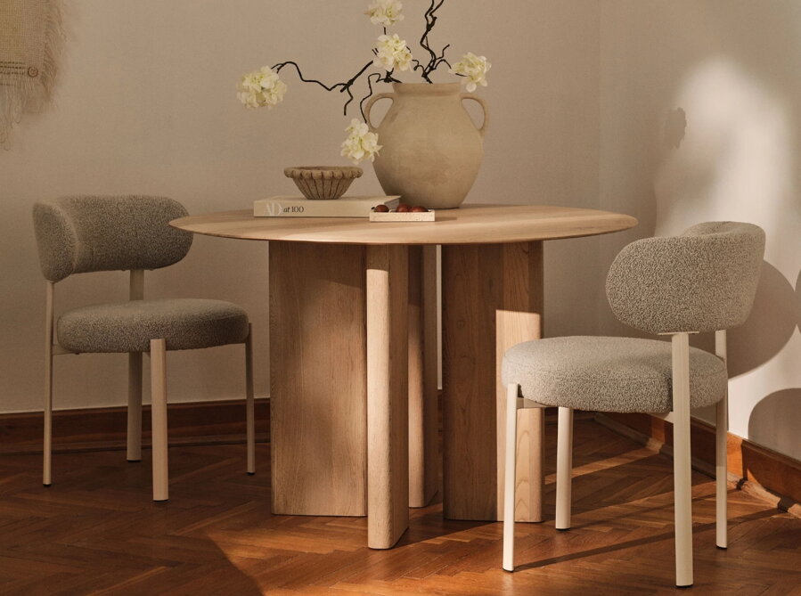 Okrúhly jedálenský stôl z dubového dreva prírodnej farby s dvoma čalúnenými stoličkami rovnakej dubovej farby.