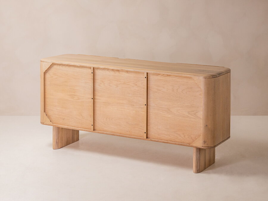 Komoda Aggie z dubového dreva prírodnej farby so šiestimi uzatvorenými policami a pohľad na jej zadnú stranu.