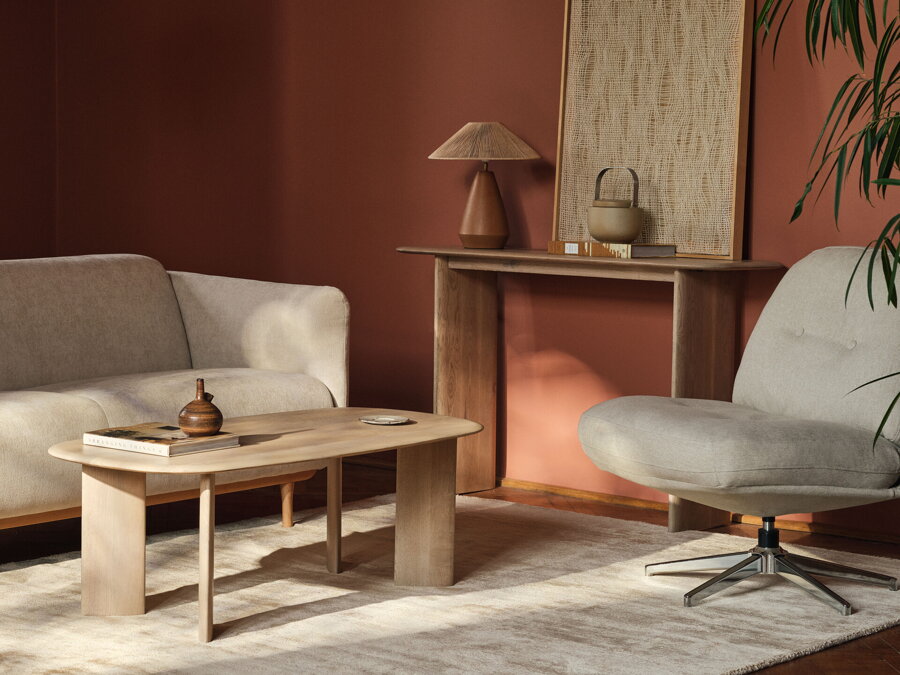Dubový konzolový stolík so stolovou lampo pri stene v obývačke s béžovou sedačkou a konferenčným stolíkom.