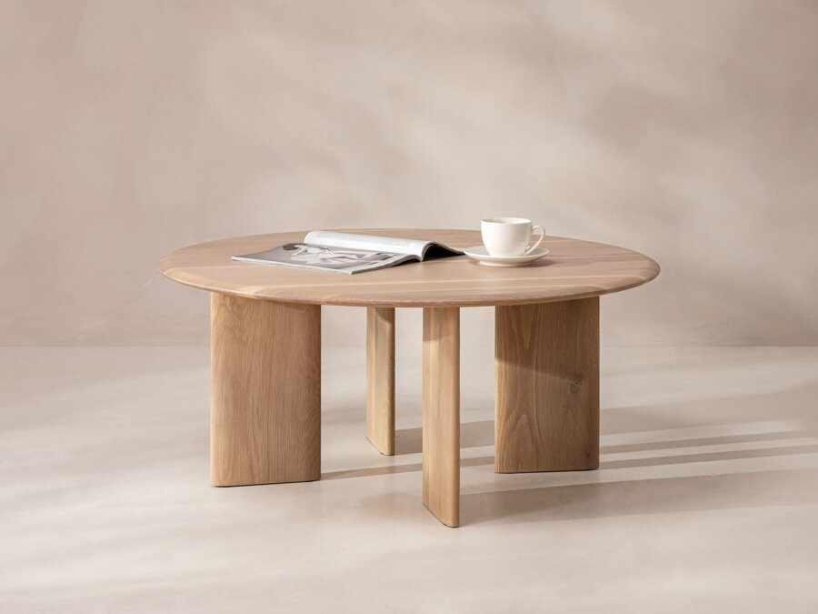 Okrúhly konferenčný stolík Aggie z dubového dreva prírodnej farby, na ktorom je biela šálka a otvorená kniha.