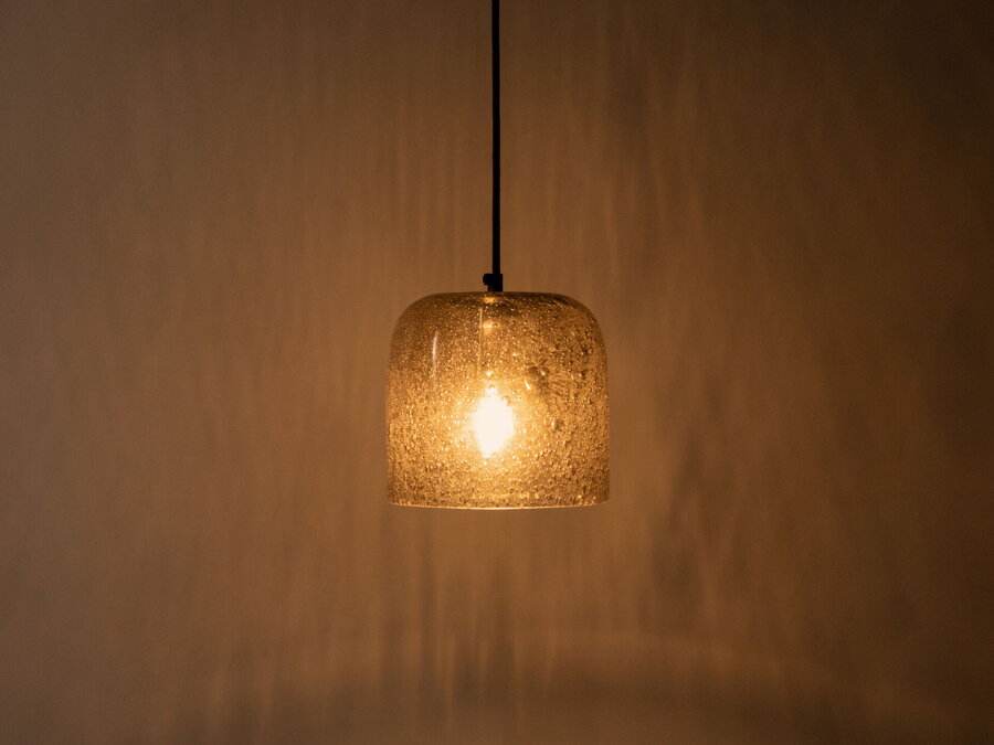 Svietiaca závesná lampa Aura s tienidlom z  bublinkového skla jantárovej farby.