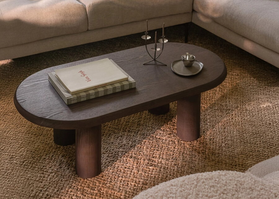 Tmavohnedý konferenčný stolík Bufi z jaseňového dreva na koberci pred pohovkou.