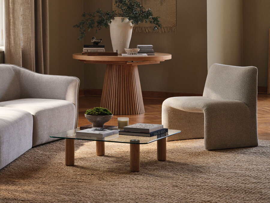 Jutový koberec Calice prírodnej farby v obývačke s tmavohnedým konferenčným stolíkom a béžovou pohovkou a kreslom.