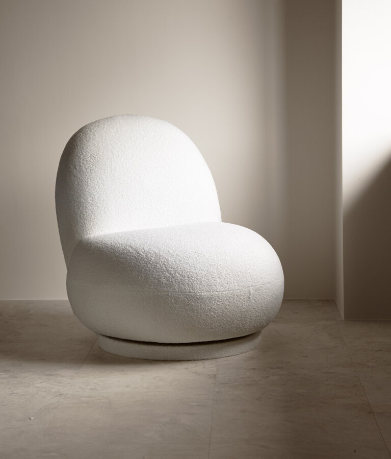 Svetlé béžové otočné kreslo na béžovej podlahe pred béžovou stenou.