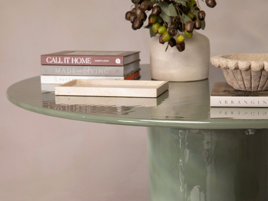 Zelený jedálenský stôl zo železa s vysokolesklou povrchovou úpravou, na ktorom sú položené knihy a váza s kvetmi.l