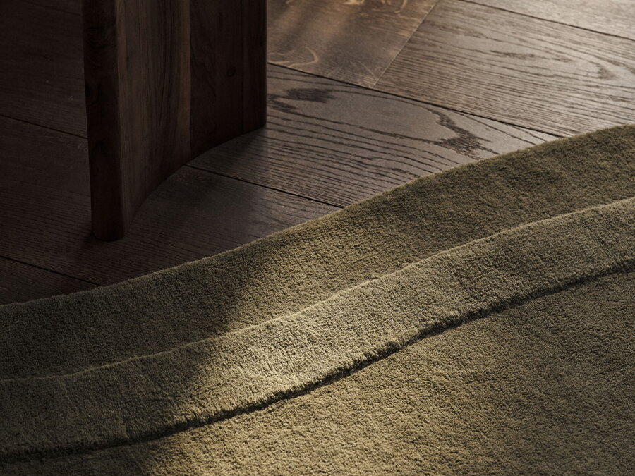 Svetlo dopadajúce na hnedozelený koberec z polypropylénu v organickom tvare na drevenej podlahe.