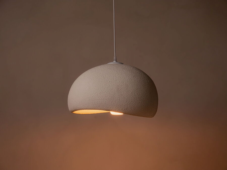 Zasvietená biela lampa v tvare polkruhu v prítmí.