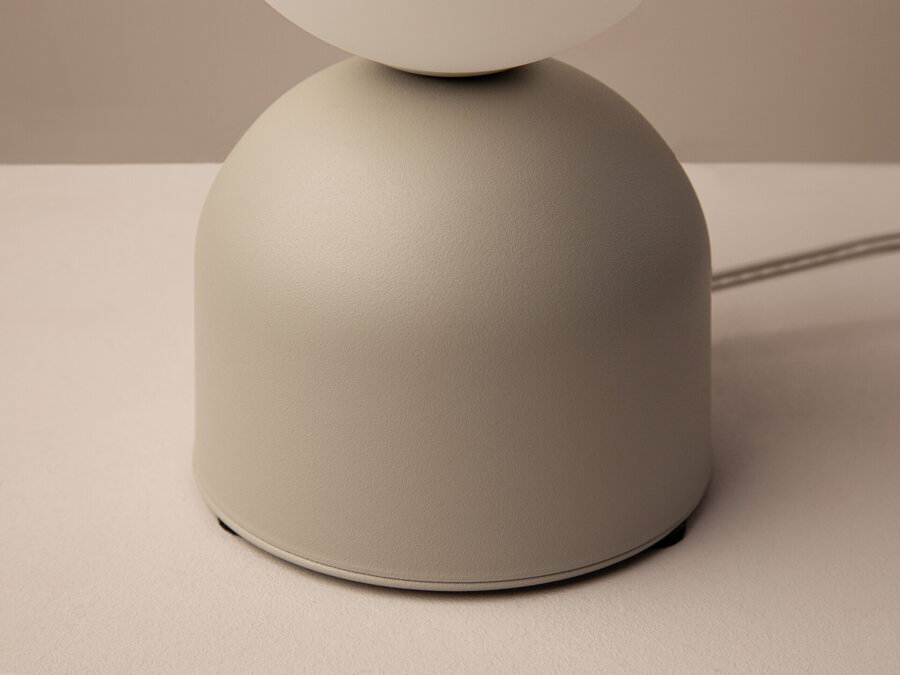 Detail na matnú béžovú kovovú základnňu lampy Ely.