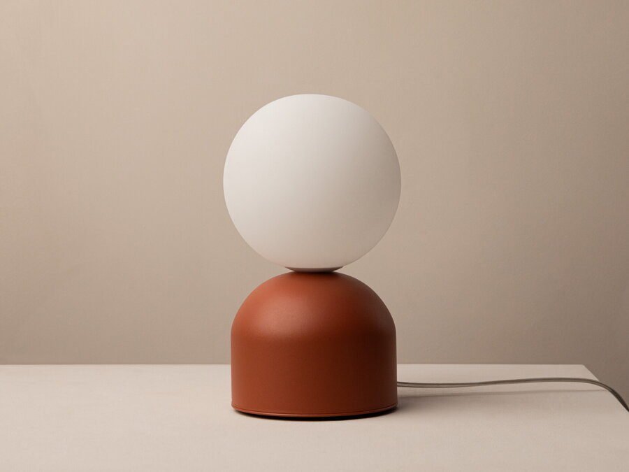 Červená stolová lampa Ely s kovovou základňou a matným bielym skleneným tienidlom v tvare gule.