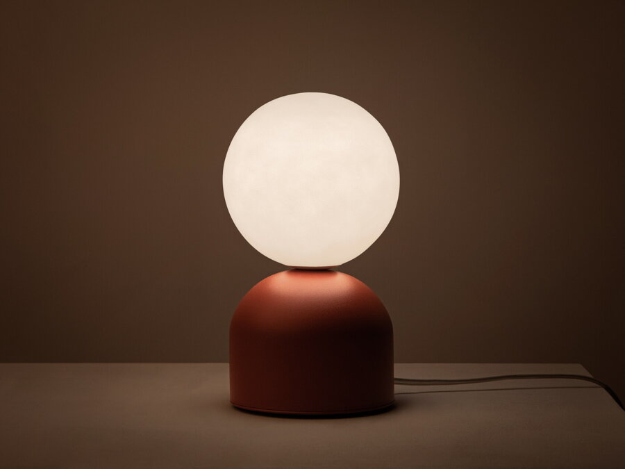 Dizajnová stolová lampa Ely s matnou červenou kovovou základňou a matným bielym skleneným tienidlom v tvare gule.