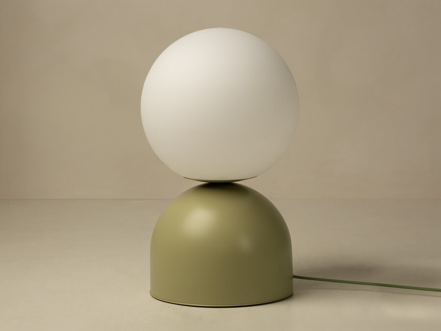 Stolová lampa Ely s matnou svetlozelenou kovovou základňou a matným bielym skleneným tienidlom v tvare gule.