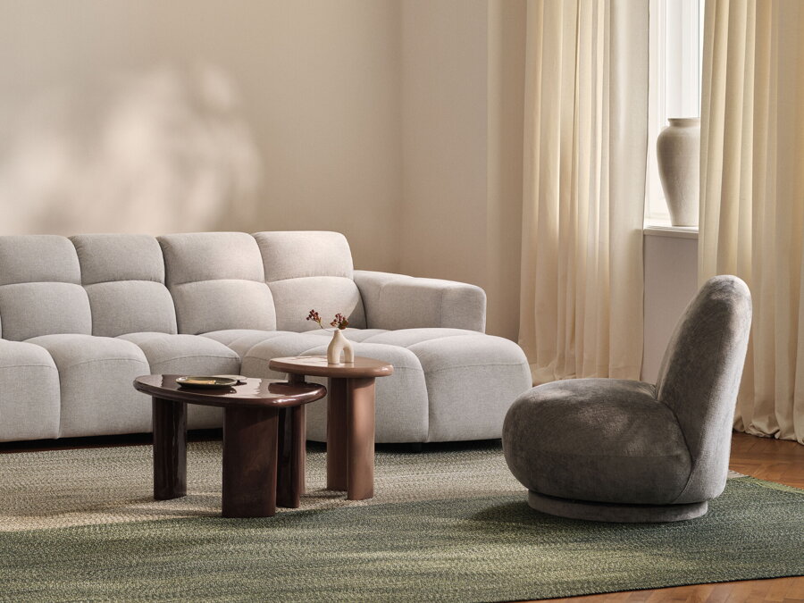 Konferenčný a príručný stolík hnedej farby s vysokým leskom v obývačke s bielou pohovkou a sivým kreslom.