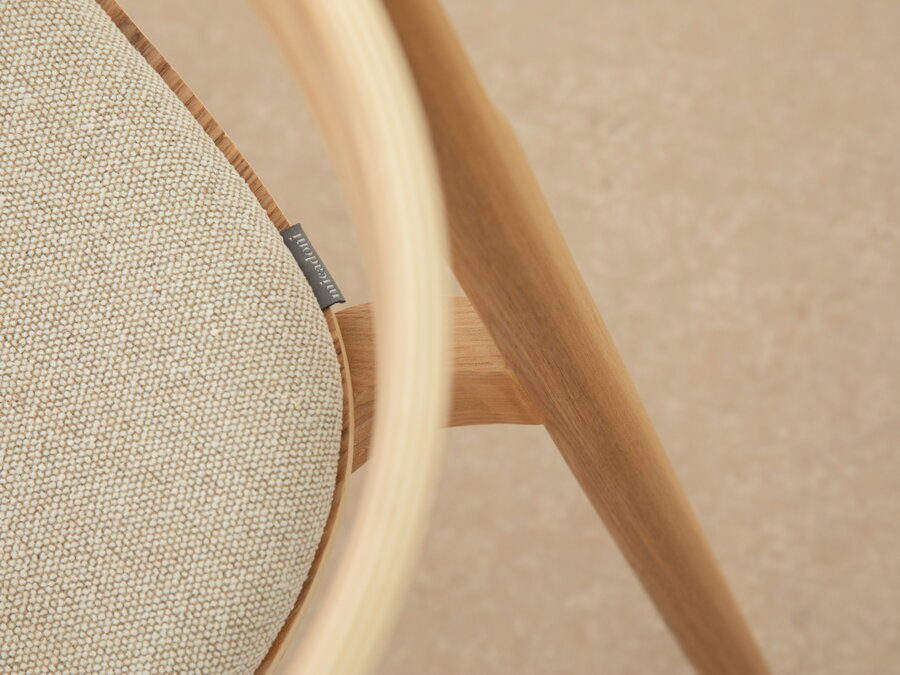 Detailný záber na zaoblené operadlo drevenej stoličky.