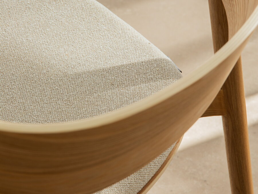 Detailný záber na zaoblené operadlo drevenej stoličky.