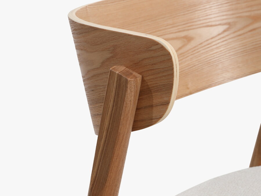 Detailný záber na zaoblené operadlo drevenej stoličky.