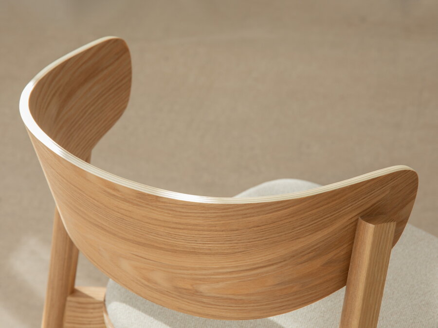 Detailný záber zo zadu na zaoblené operadlo drevenej stoličky.