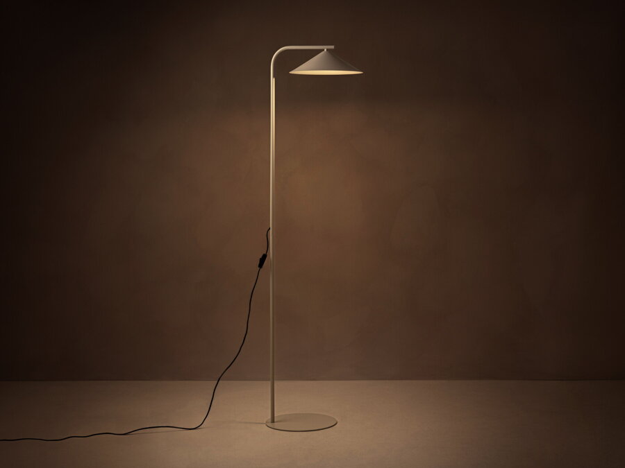 V tme rozsvietená stojanová lampa Nocte s tienidlom v tvare kužela, z kvalitného matne lakovaného kovu béžovej farby.
